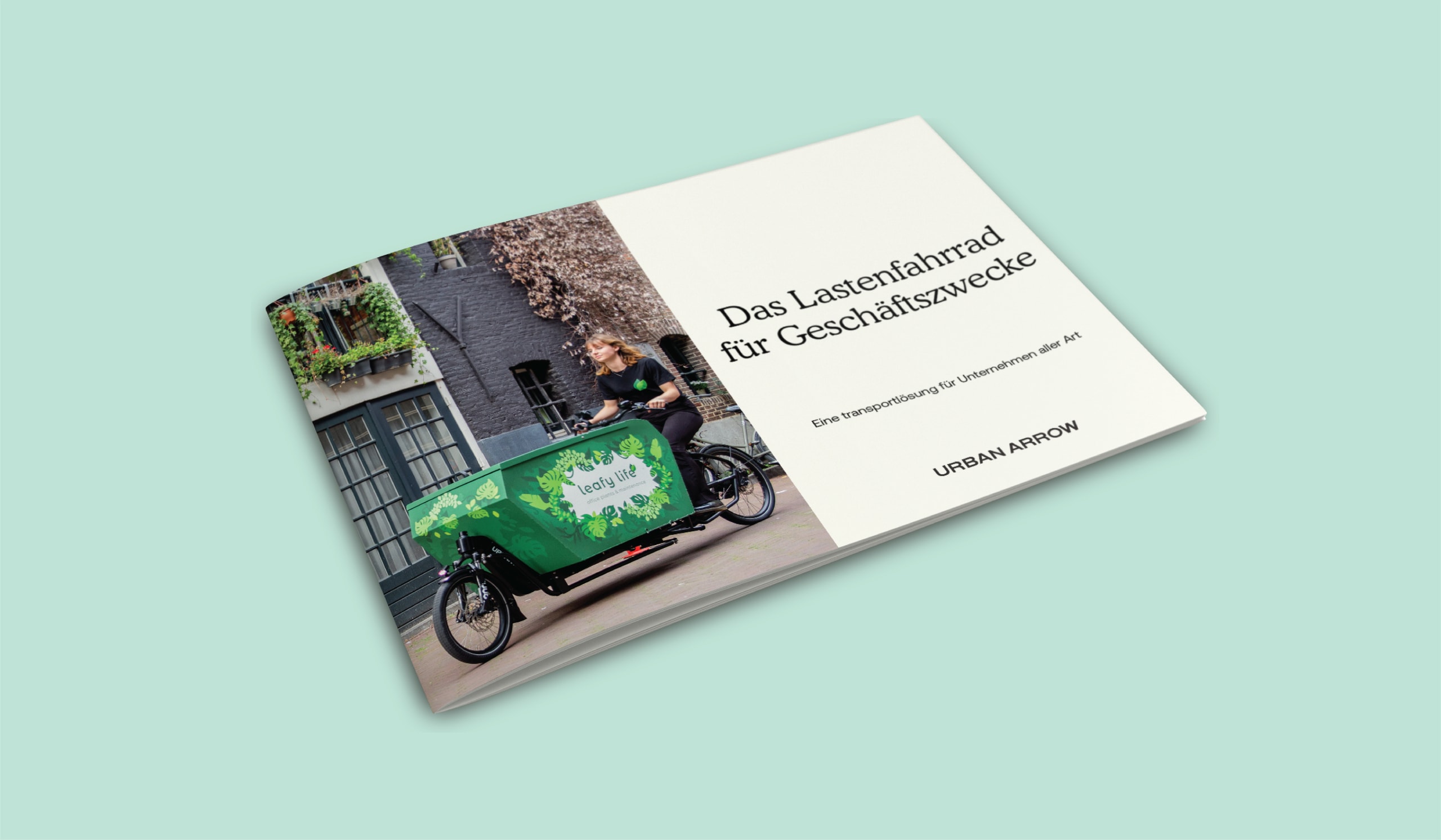 The image shows a brochure with a cover displaying a person riding a cargo bike in an urban setting. German text reads, Das Lastenfahrrad für Geschäftszwecke with URBAN ARROW at the bottom. The bike has a green container with city illustrations.